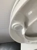 A close-up view of a white toilet seat with a sensor or mechanism visible. Produktbild-Vorschau