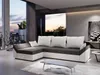 A modern living room with a sectional sofa, coffee table, and large window overlooking a sunset. Náhled obrázku produktu