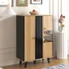 A modern cabinet with a wood and black finish, displayed in a room setting with artwork and a decorative statue. Produktbild-Vorschau