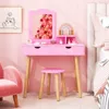 A pink children's vanity set with a stool, mirror, and accessories, set against a pink wall. Produktbild-Vorschau