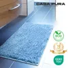 A light blue bath mat is placed on a tiled floor next to a cabinet. Anteprima dell’immagine prodotto