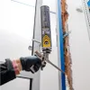 A person is using a can of spray foam to fill a gap in a wall next to a door frame. Produktbild-Vorschau