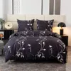 A neatly made bed with a dark duvet cover and pillowcases featuring a white leaf pattern. Náhled obrázku produktu