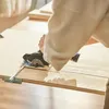 A person is using a Dremel cordless circular saw to cut a piece of wood on a table. Produktbild-Vorschau