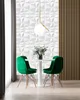 A modern dining area with a white table, four green chairs, and a geometric white wall paneling. Produktbild-Vorschau