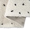 A close-up view of a beige rug with black polka dots, showing the texture of the high pile and the underside of the rug. Produktbild-Vorschau