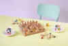 A wooden memory game with colorful pegs and two cups of coffee on a yellow table with a light purple background. Produktbild-Vorschau