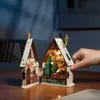 A hand is shown interacting with a miniature Christmas house decoration. Produktbild-Vorschau