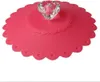 A pink silicone cup lid with a clear diamond-shaped handle is shown against a white background. Produktbild-Vorschau