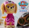 A plush toy of the character Skye from Paw Patrol Air Rescue, standing in front of a blurred background with a Paw Patrol logo and goggles. Podgląd zdjęcia produktu