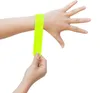 A person's arm and hand are shown with a neon yellow reflective band being applied to the wrist. Produktbild-Vorschau