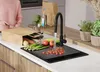 A person is preparing vegetables in a kitchen next to a sink with a faucet running. Produktbild-Vorschau
