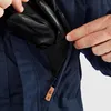 A close-up shot of a person's hands putting black leather gloves into a zippered pocket on a blue jacket. Produktbild-Vorschau