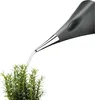 A gray watering can is watering a green plant. Anteprima dell’immagine prodotto