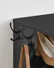 A close-up of a black shoe rack with hooks on the side, a brown handbag hanging from one of the hooks, and shoes on the shelves. Náhled obrázku produktu