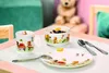 A children's breakfast set with teddy bear illustrations is laid out on a white tray, with a blurred teddy bear in the background. Produktbild-Vorschau