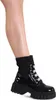 A close-up shot of a woman's lower leg wearing a black patent leather boot with glitter accents.