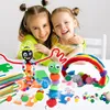 Two young girls are hugging and smiling, surrounded by various craft supplies and handmade creations. Produktbild-Vorschau