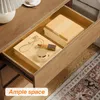 An open drawer of a wooden nightstand, showing stored items like notebooks, jewelry, and makeup. Produktbild-Vorschau