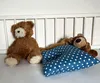 Two teddy bears and a baby pillow are arranged in a crib. Produktbild-Vorschau