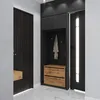 A modern entryway with a dark wood door, a black storage unit with wood drawers, and another black door with a vertical light strip. Produktbild-Vorschau