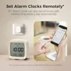 A person is using a smartphone to control a Bluetooth alarm clock, which is displayed alongside a wall-mounted switch and a cup of coffee. Podgląd zdjęcia produktu