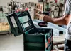 A person is holding a cordless drill over an open tool case in a workshop. Produktbild-Vorschau