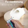 A hand holding a remote control points it towards a white bunny-shaped night light. Produktbild-Vorschau