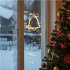 A Christmas bell light hanging in a window with a Christmas tree and snowy outdoor scene in the background. Produktbild-Vorschau