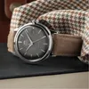A close-up of an Orient watch with a brown strap, resting on a dark surface next to a patterned fabric. Voir les images du produit