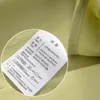 A close-up of a fabric label attached to a light green textile, likely bedding. Produktbild-Vorschau