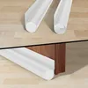 Two views of a white foam door draft stopper on a wooden floor and under a wooden cabinet. Náhled obrázku produktu