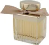Elegant geriffelter Glasflakon Chloé Absolu mit goldener Kappe und seitlich gebundener Schleife in Goldbeige mit feinem Glanz. Podgląd zdjęcia produktu