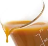 A close-up shot of a viscous, orange liquid being poured from a glass beaker. Podgląd zdjęcia produktu