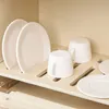 A close-up view of a wooden dish rack holding white plates and cups. Náhľad obrázku produktu