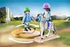 Two children playing with a toy horse and riding accessories in a natural outdoor setting with a waterfall in the background. Produktbild-Vorschau