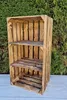 A wooden crate shelf unit is displayed outdoors against a backdrop of green foliage and a light gray surface. Náhled obrázku produktu