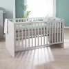 A baby crib with bedding in a room with natural light. Produktbild-Vorschau