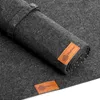 A close-up view of a rolled-up felt desk mat with leather branding tags. Produktbild-Vorschau