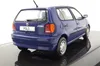A blue Volkswagen Polo model car is shown from the rear three-quarter view, placed on a reflective black surface against a white background. Produktbild-Vorschau