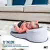 A baby lying on an inclined baby support pillow on a rug in front of a sofa. Produktbild-Vorschau