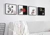 Four framed vinyl record art pieces are displayed on a white wall above a light gray sofa with a white throw blanket. Produktbild-Vorschau