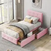 A pink upholstered bed with storage drawers is shown in a bedroom setting. Produktbild-Vorschau