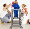 A family is painting a wall, with a child standing on a learning tower. Produktbild-Vorschau
