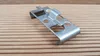A metal clip is placed on a wooden surface. Produktbild-Vorschau