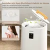 A white towel warmer with a lid open, showing internal heating elements. Inset images show a close-up of an aromatherapy holder and a woman smelling a towel. Anteprima dell’immagine prodotto