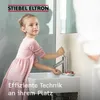 A young girl is washing her hands at a sink with a faucet. Produktbild-Vorschau