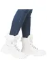 A person wearing blue jeans and white winter boots. Podgląd zdjęcia produktu