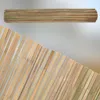 A rolled-up bamboo mat and a section of an unrolled bamboo fence are shown against a blurred background. Podgląd zdjęcia produktu