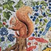 A close-up view of a jigsaw puzzle depicting a squirrel on a tree stump surrounded by berries, mushrooms, and foliage. Podgląd zdjęcia produktu